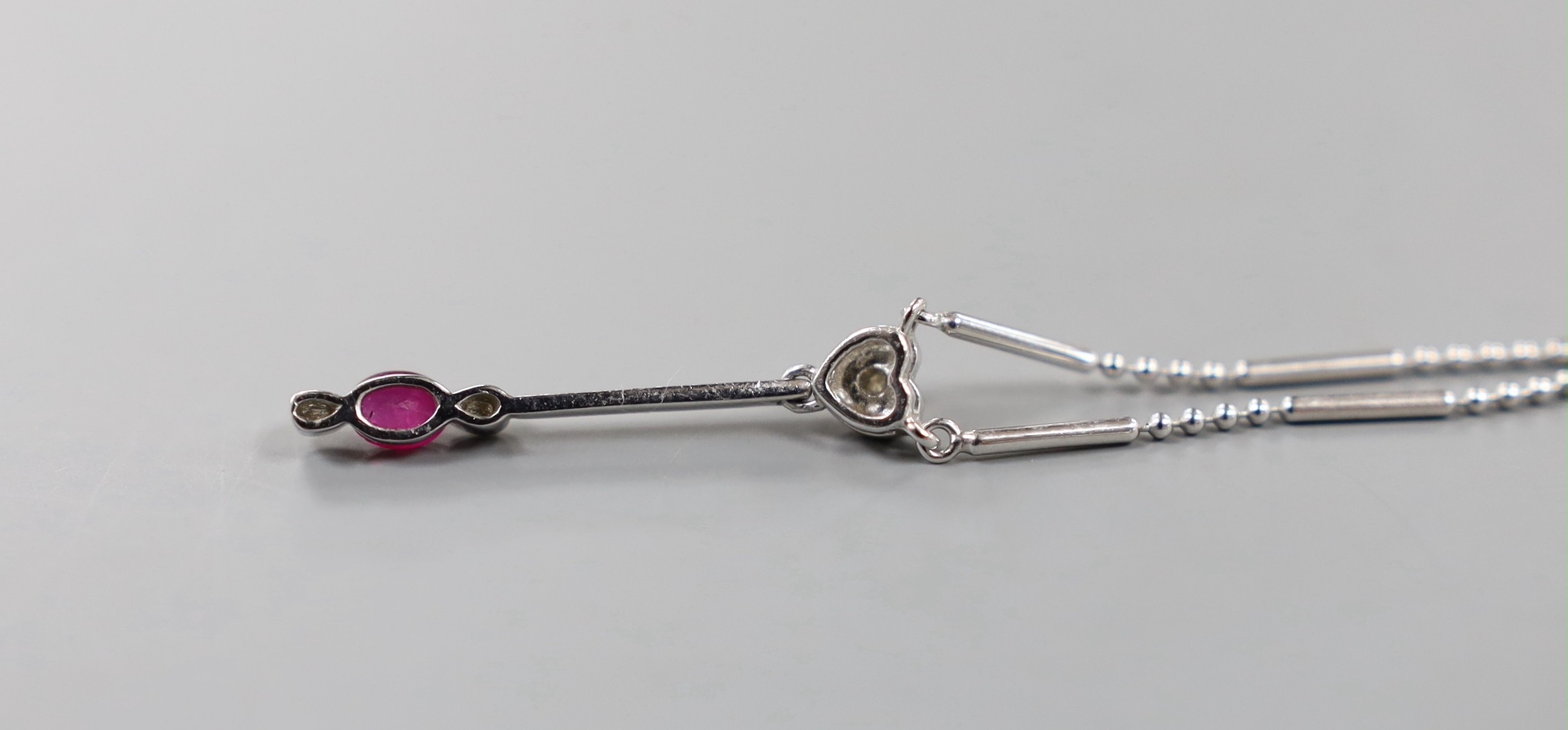 An 18ct white gold (750) pendant with ruby drop on bar and long link chain with silver clasp, chain 38cm, gross 4.8 grams.